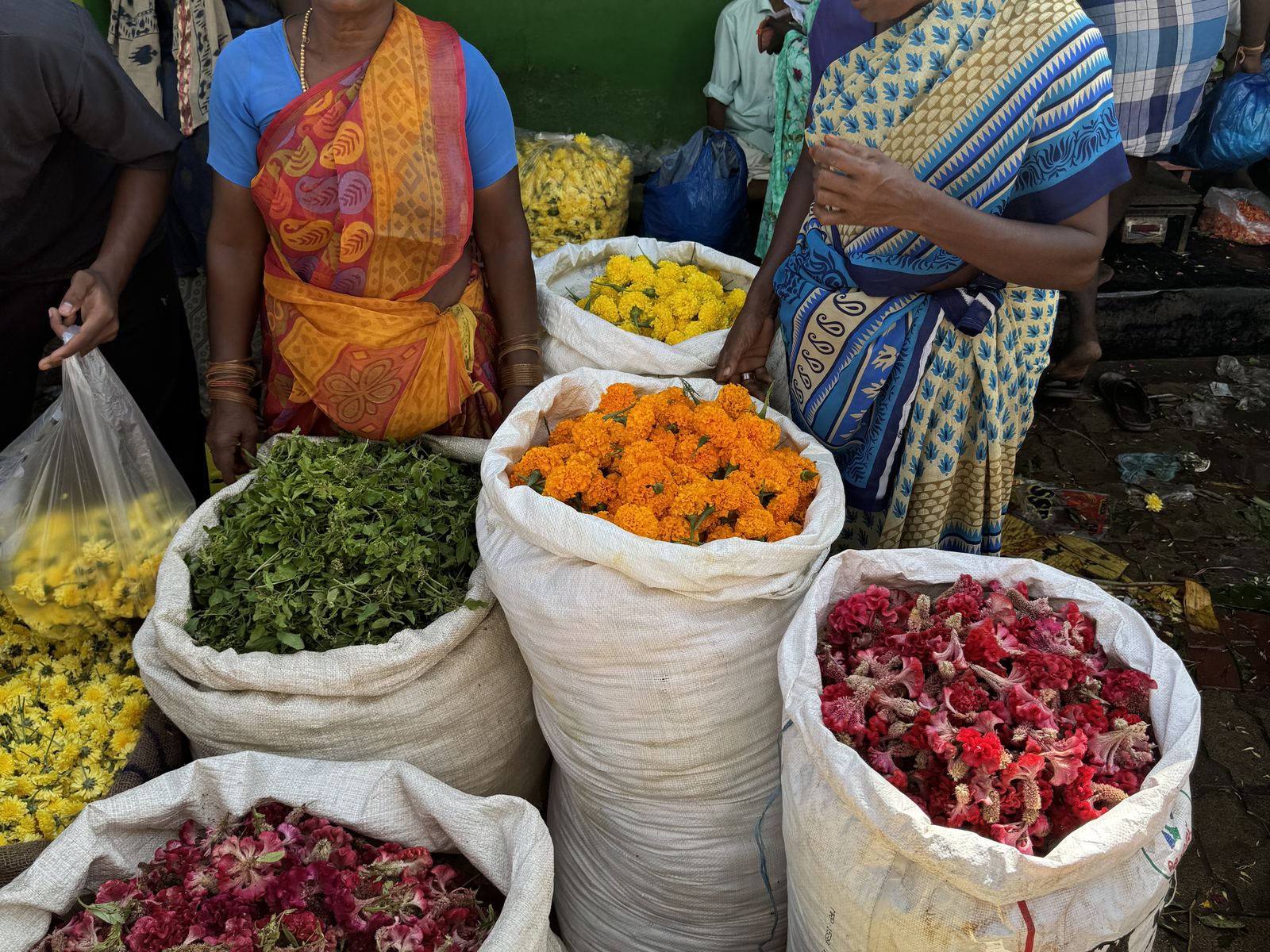 Vendedoras junto a sacos de petalos de rosa y calendula en el mercado de flores de Madurai, Tamil Nadu