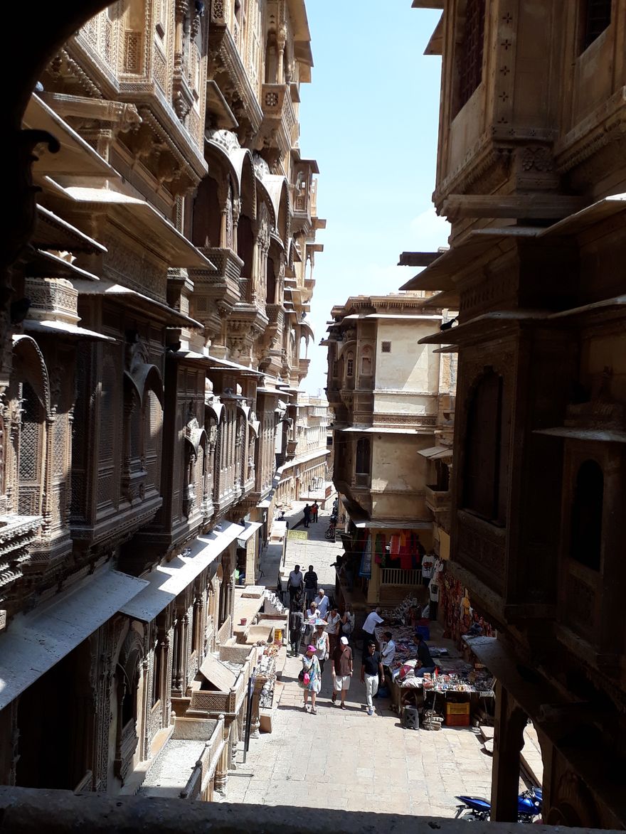 Calle estrecha de la ciudad vieja de Jaisalmer entre fachadas de havelis con balcones de arenisca tallada