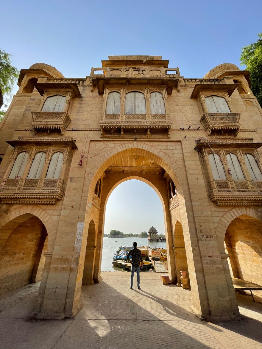 Puerta de arenisca tallada de Tilon ki Pol enmarcando el lago Gadisar, en Jaisalmer