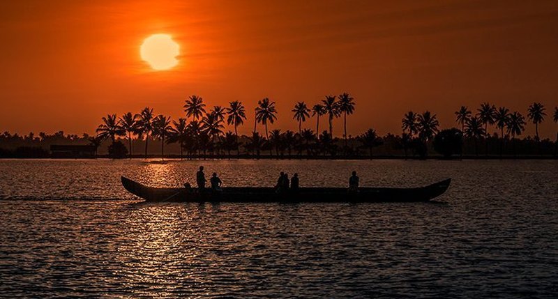 Canoa tradicional recortada contra el atardecer en los backwaters de Kerala