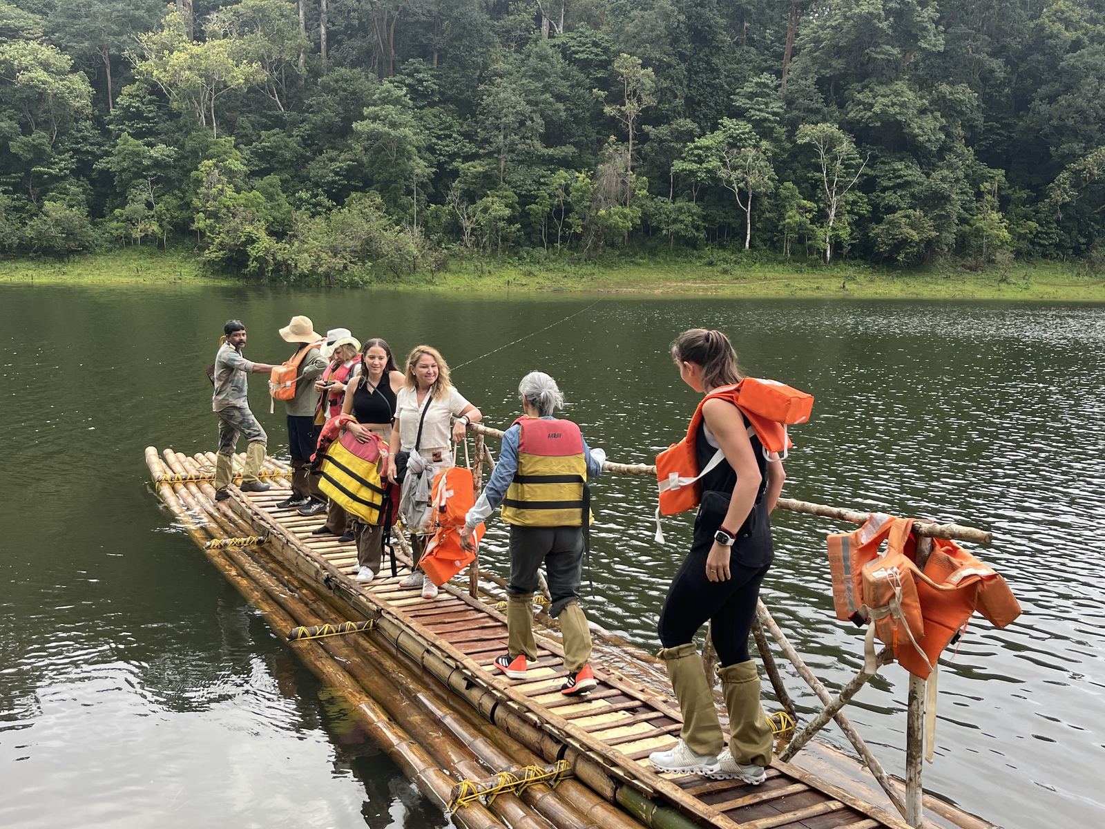 Viajeros en una balsa de bambu sobre un lago rodeado de selva en los Ghats occidentales, sur de la India