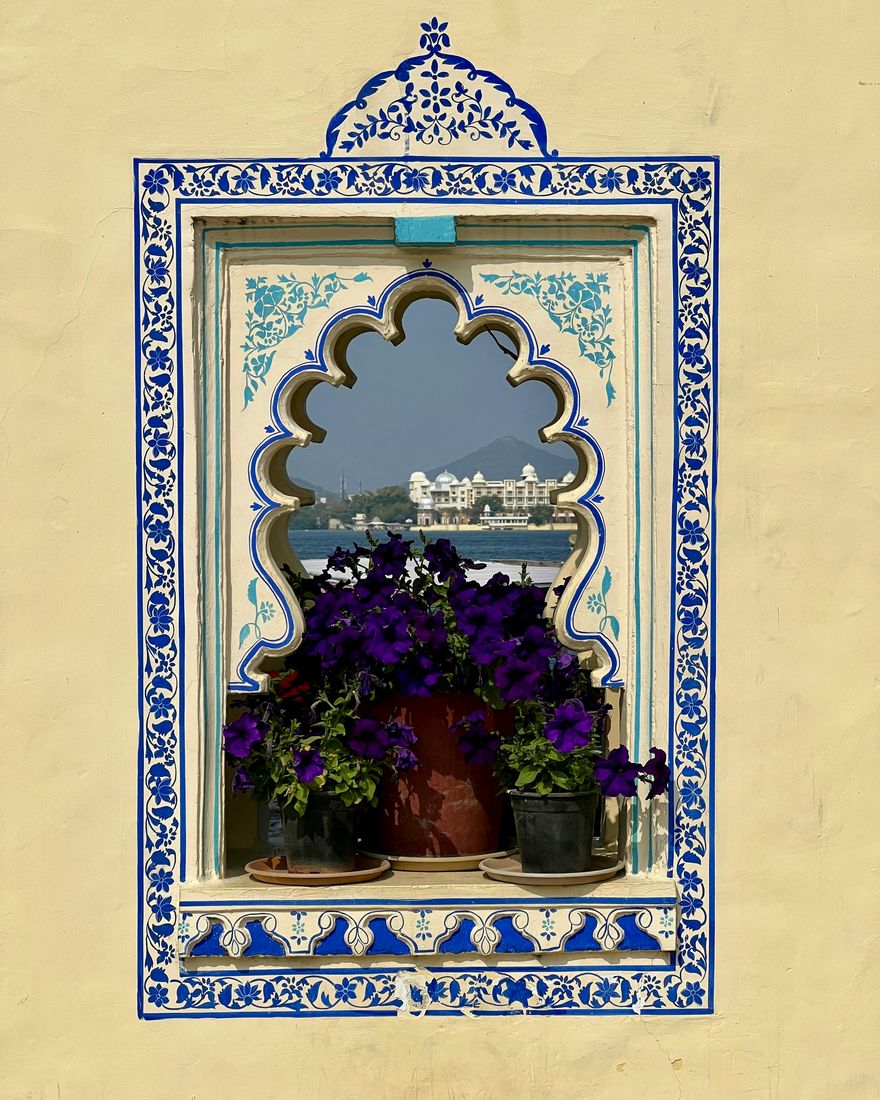 Ventana con marco pintado de azul que enmarca el lago Pichola, en Udaipur
