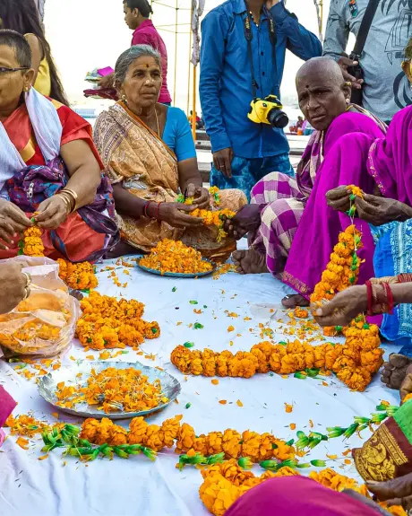 Mujeres tejen guirnaldas de caléndula en un mercado de flores