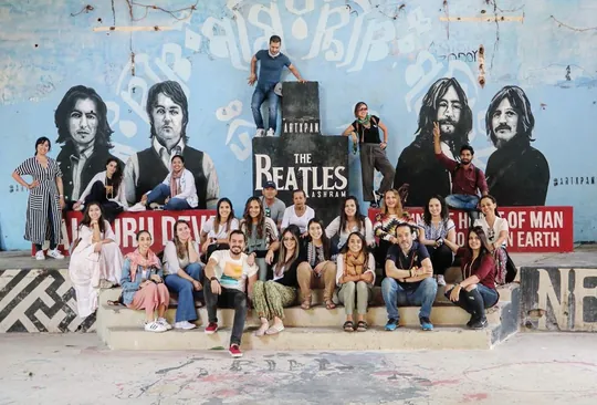 Grupo de viajeros sentado ante el mural de los Beatles en el ashram de Rishikesh
