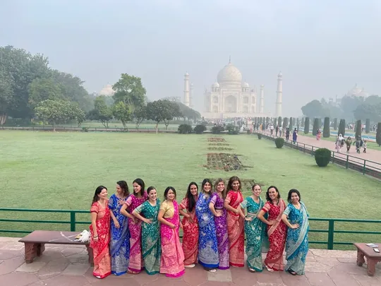 Grupo de viajeras vestidas con saris de colores frente al Taj Mahal, en Agra