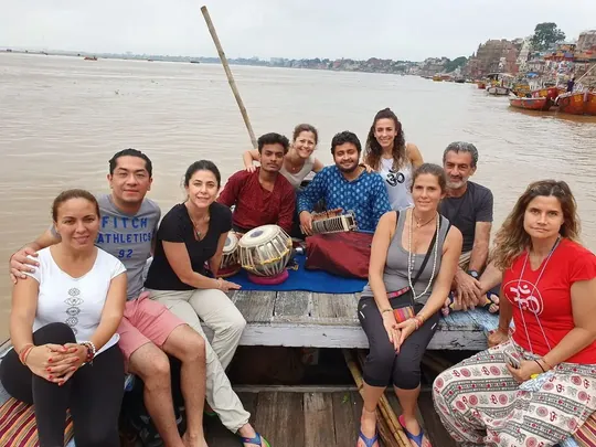 Viajeros sentados en una barca por el Ganges en Varanasi, junto a un músico con tabla