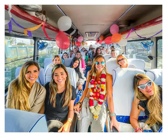 Viajeras con guirnaldas de flores dentro de un autobús decorado con globos de bienvenida