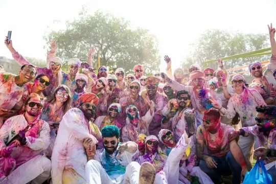 Grupo de viajeros cubiertos de color durante la fiesta de Holi, en 2025