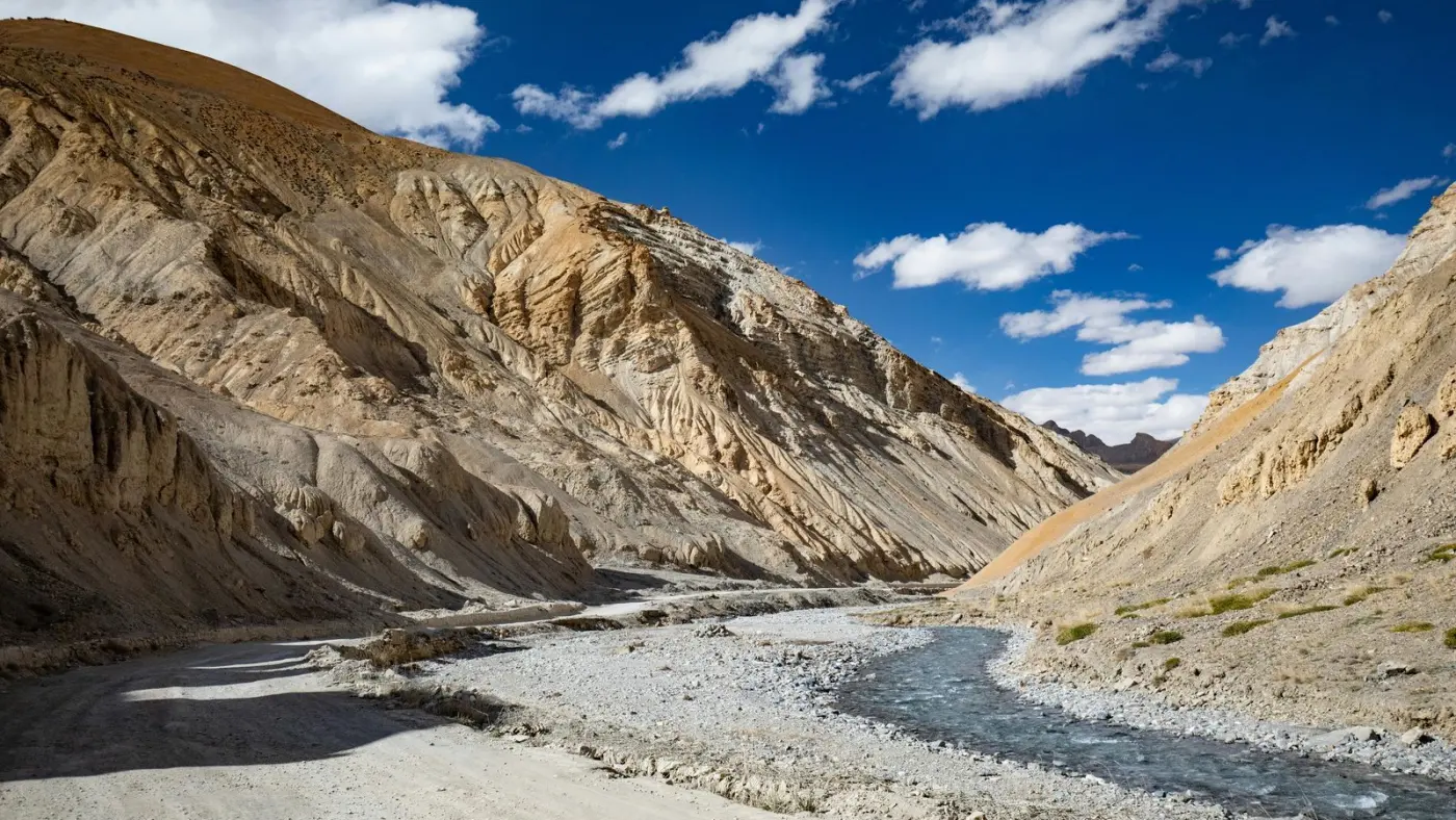 Carretera de montaña siguiendo un río de aguas glaciares en el Himalaya indio