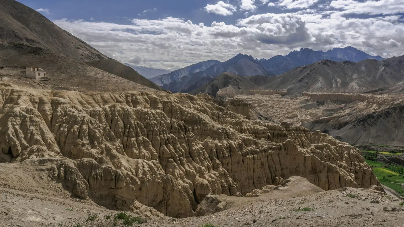 Formaciones de tierra erosionada bajo un cielo de nubes altas, camino de Ladakh