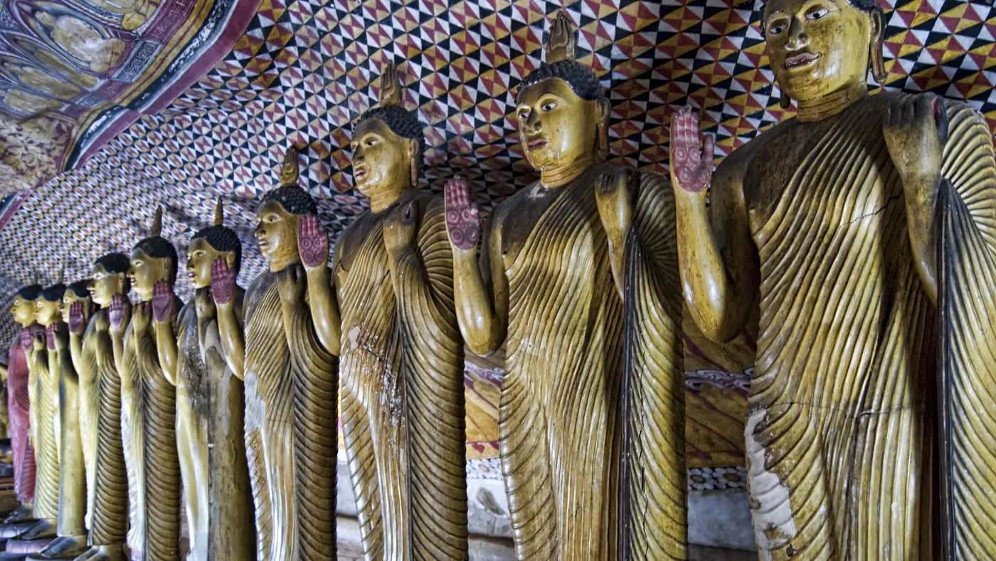 Hilera de budas dorados bajo los frescos del templo rupestre de Dambulla